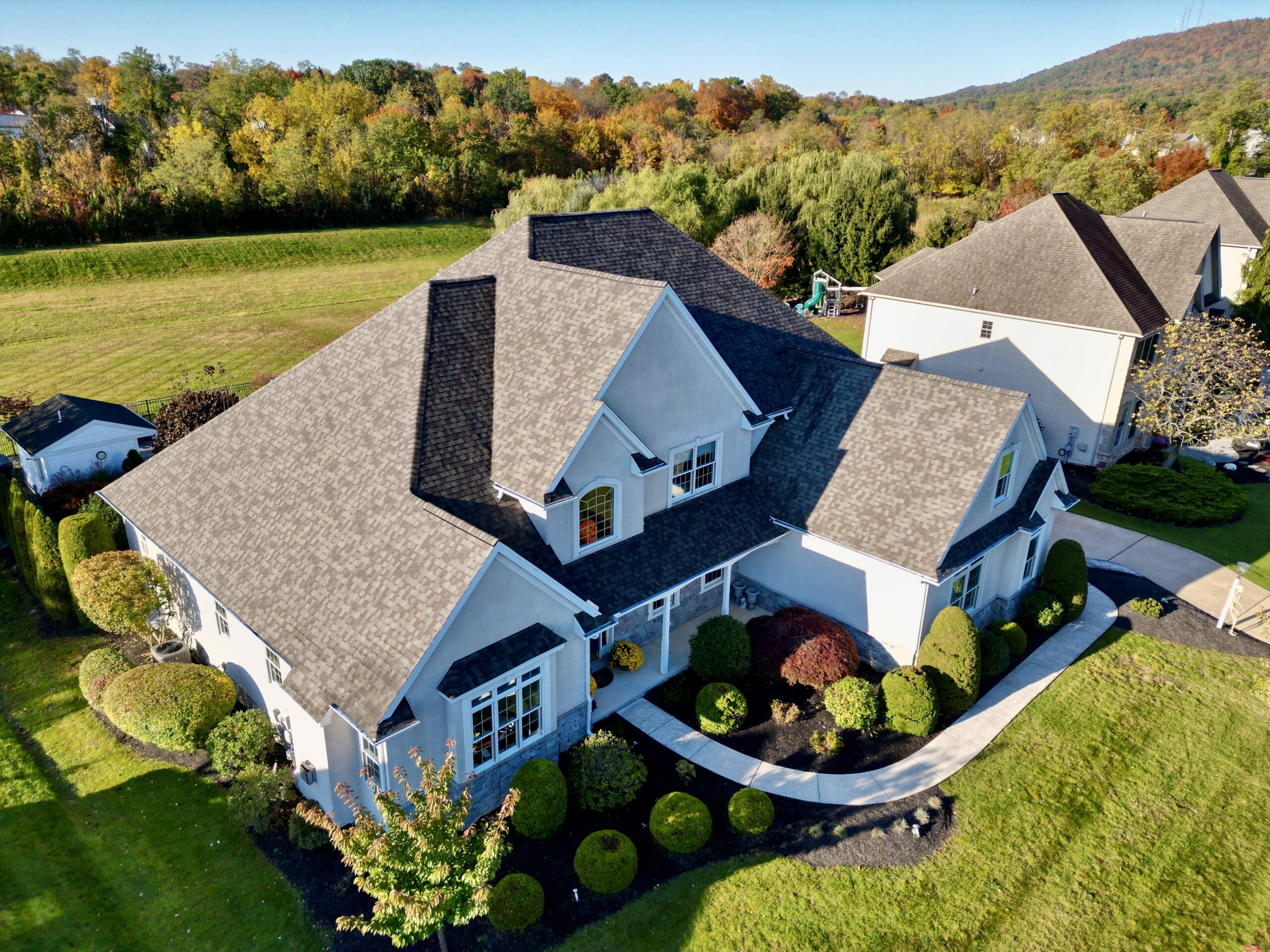 Aerial shot of large home with landscaping, new shingled roof 