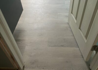 A light-colored wooden floor is visible through an open door, with part of a cabinet and another doorway on the left side of the image.